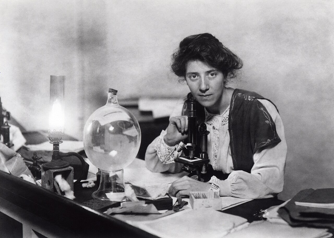 Marie Stopes at her laboratory in the Victoria University of Manchester, studying "what appear to be coal ball slides" (Source for slides: University