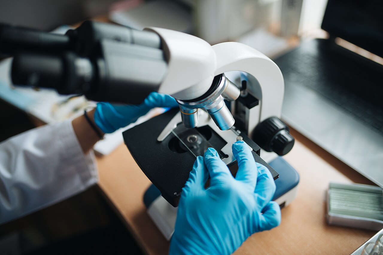 Close-up of a lab technitian adjusting a microscope glass slide